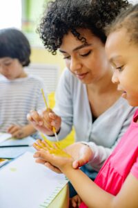 Woman-Painting-A-Girl-S-Hand-With-Yellow-Color